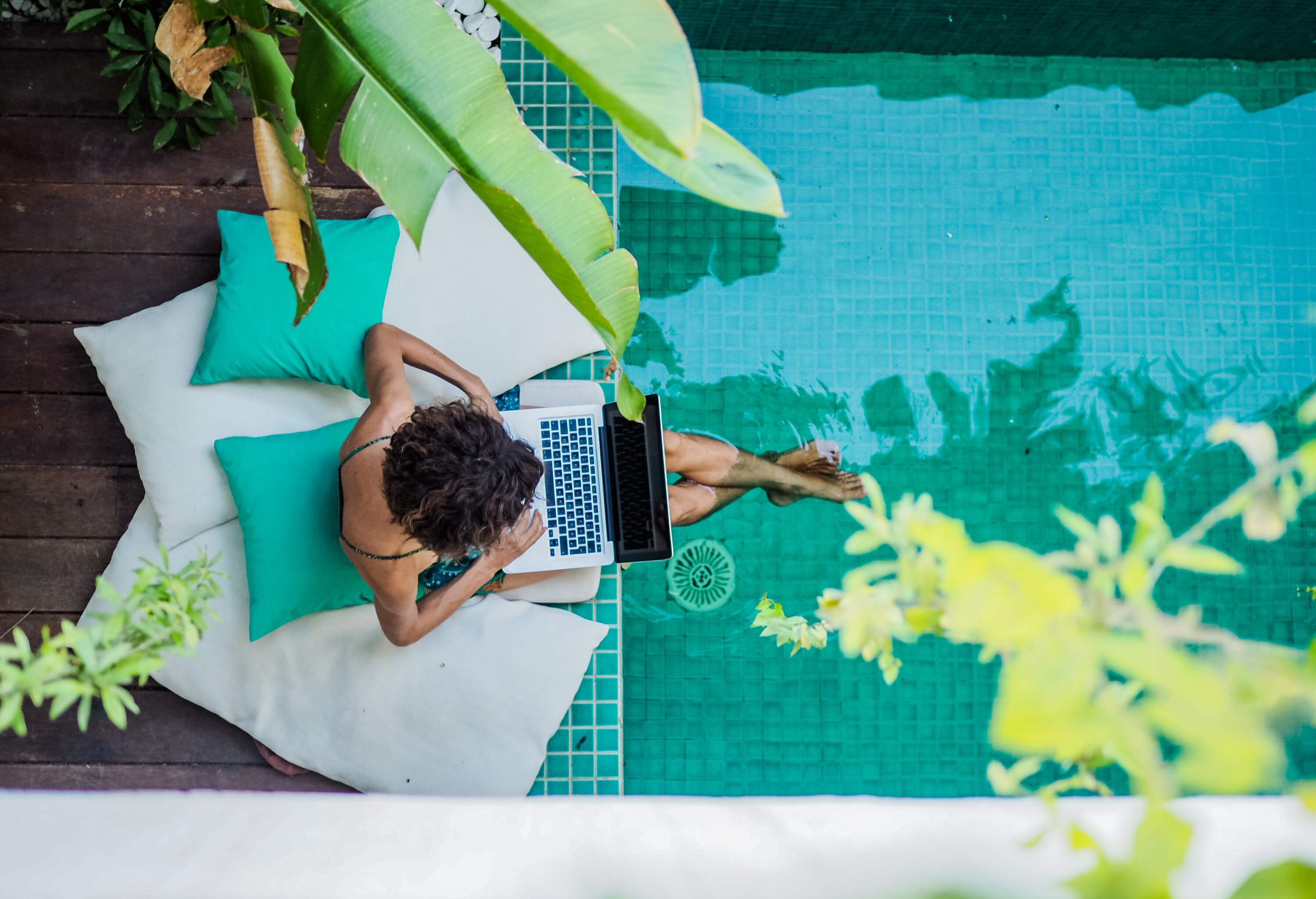 theme_woman_person_digital-nomad_working_remotely_pool_device_laptop_shutterstock_1742840084-1
