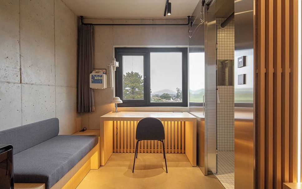 Playce Camp Jeju 真實 compact 客房內工作桌、窗與浴室空間